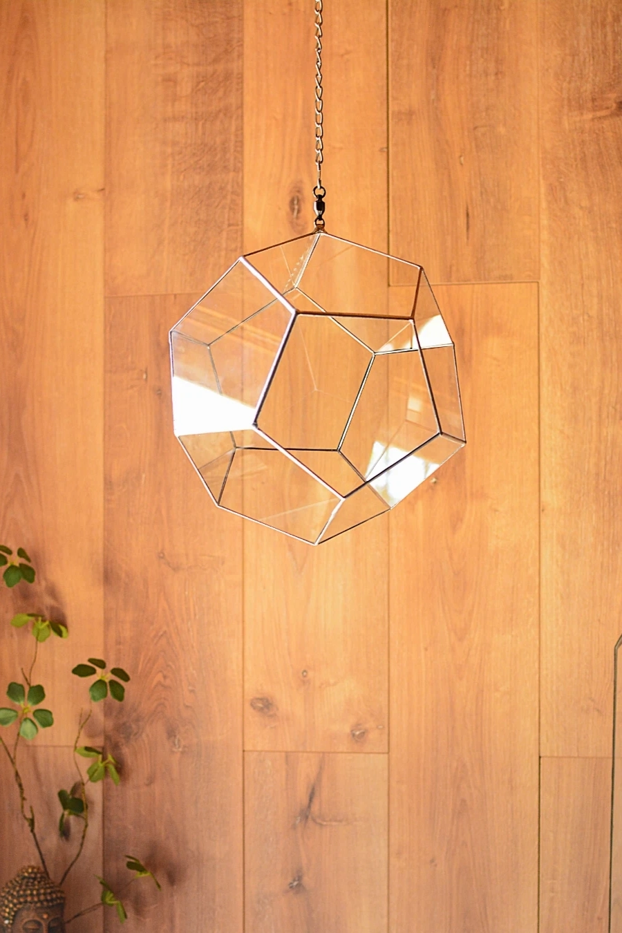 Dodecahedron hanging on the wooden wall, in front of the Buddha